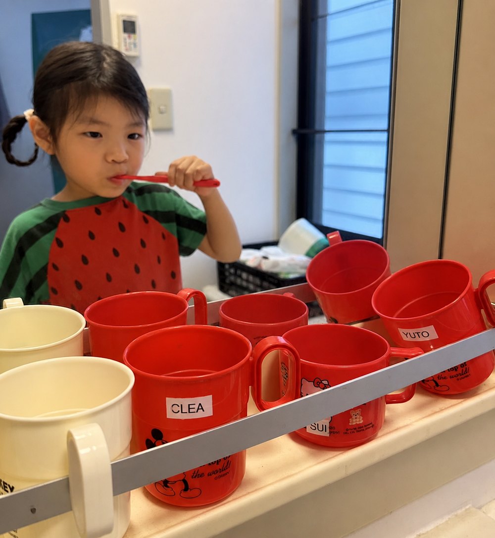 A child brushing teeth after lunch with their named cup