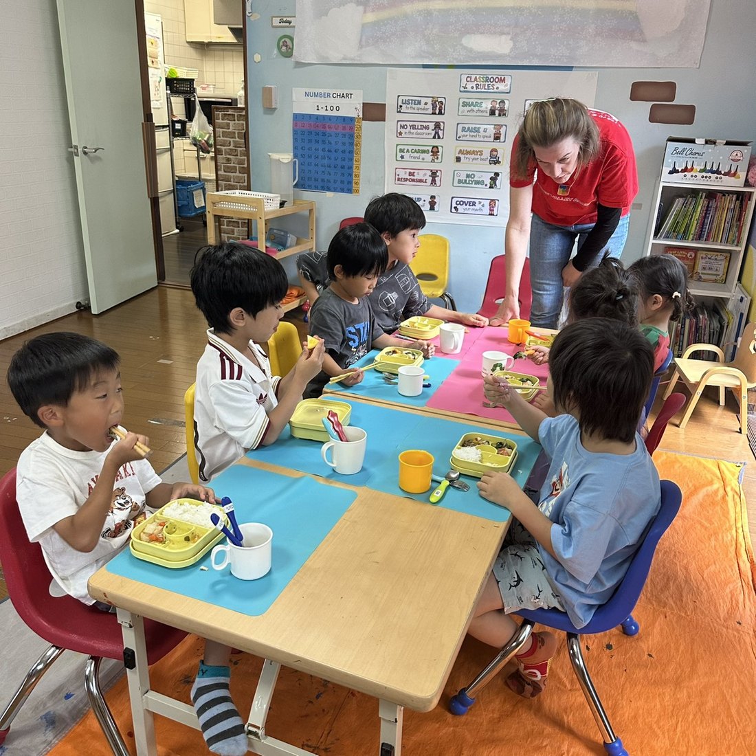 Children enjoying their bento lunch together with a native teacher