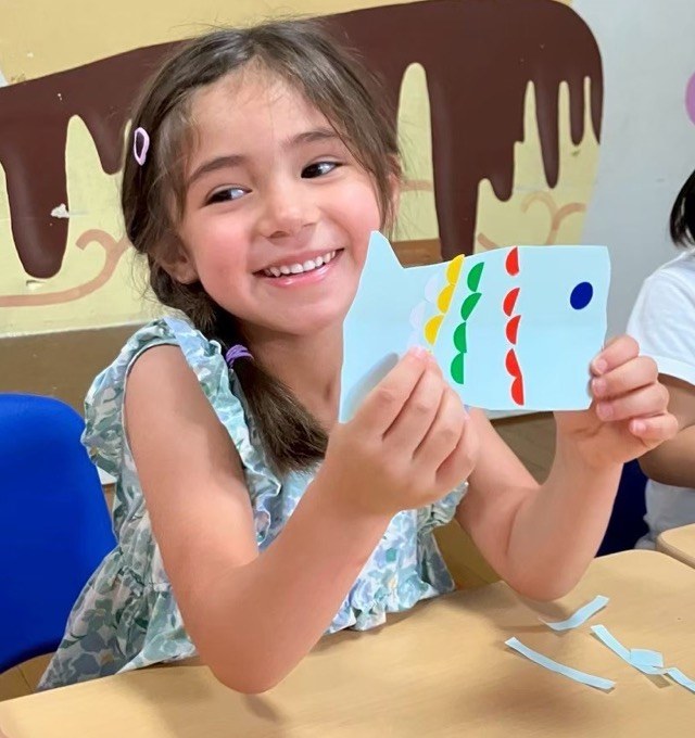 An older child proudly showing off their handmade craft