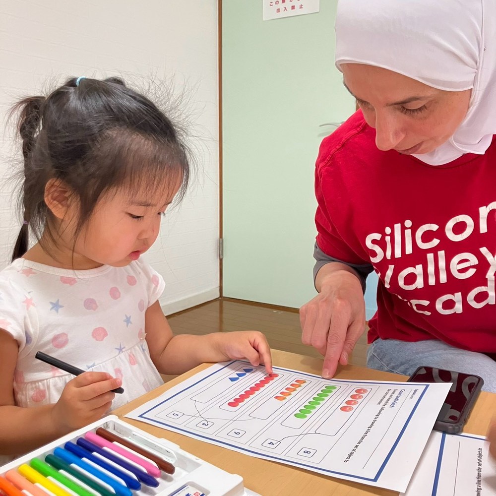 A child working on a counting task with a teacher